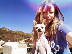 Photo of Kayley Cuoco and her white dog with ears up.