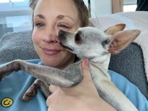 Kaley Cuoco holding a small white dog.