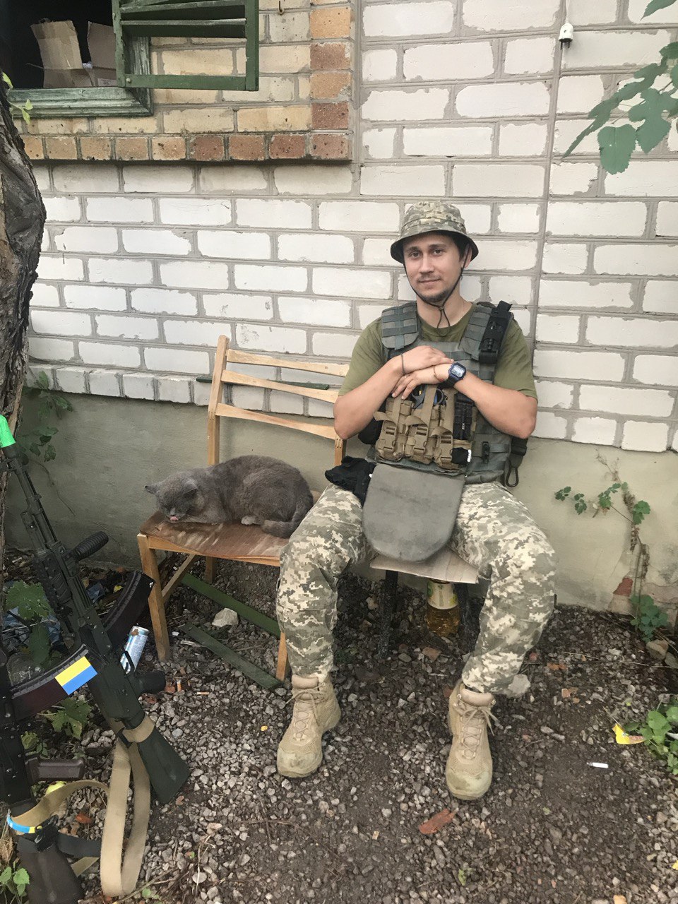 Photo of a soldier sitting next to a grey cat.