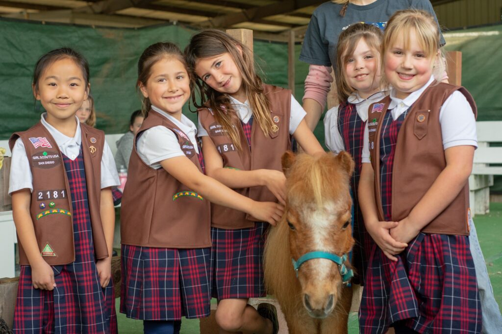 Brownies (Girl Scouts) are standing around a mini horse