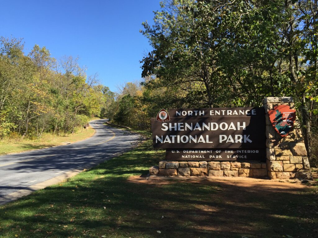 A sign that reads Shenandoah National Park next to a road surrounded by trees