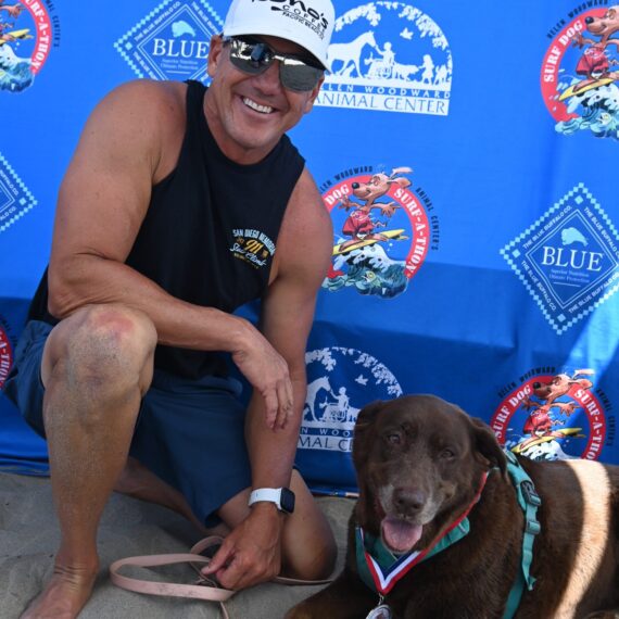 A man smiling at the camera next to his brown dog