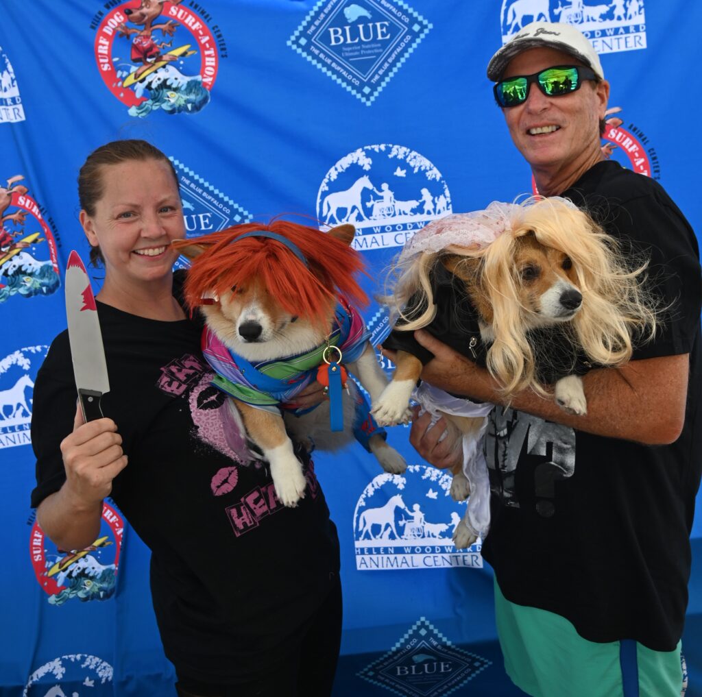 Two dogs dressed in costume with their owners