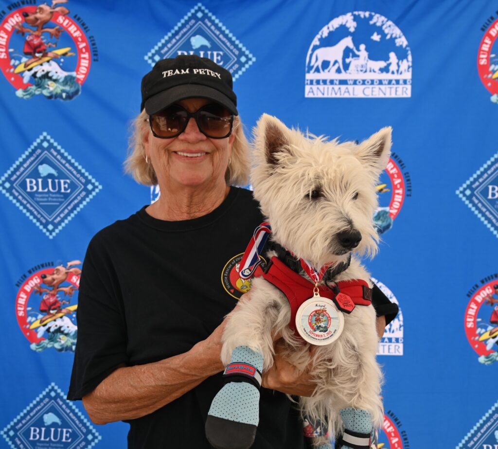 A dog receiving an award for surfing and his owner