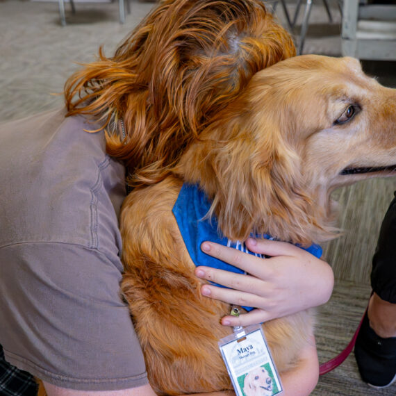 Woman bending down hugging a dog