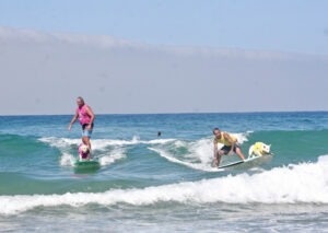 2 humans and 2 dogs surfing in Del Mar at Surf Dog Surf a Thon 
