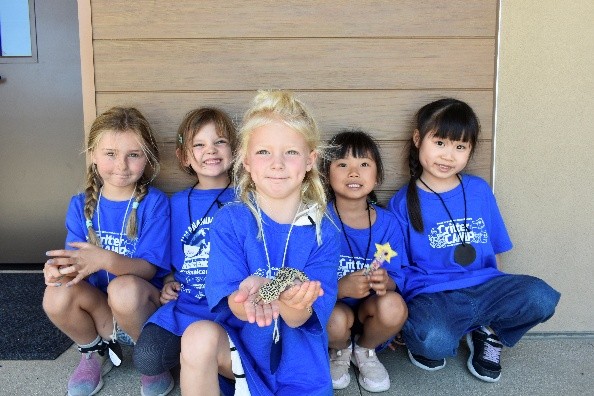 Group of children, child in the middle holding a Gecko